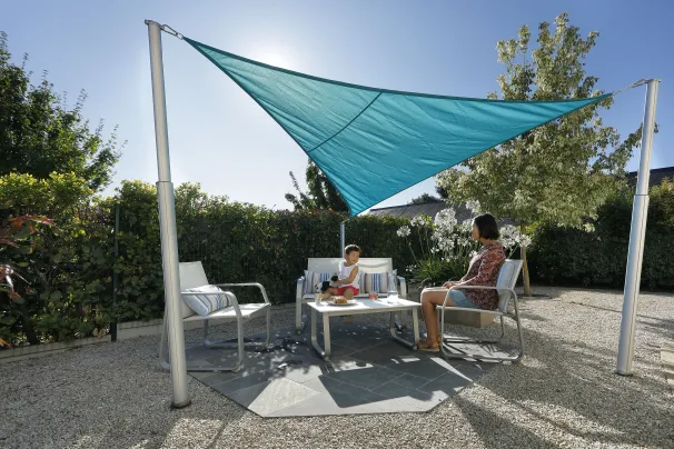 Voile d’ombrage rectangulaire beige sur terrasse, abrite un salon de jardin du soleil direct