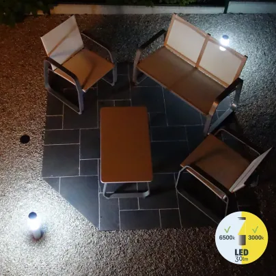 Salon de jardin éclairé par la borne solaire, ambiance lumineuse.